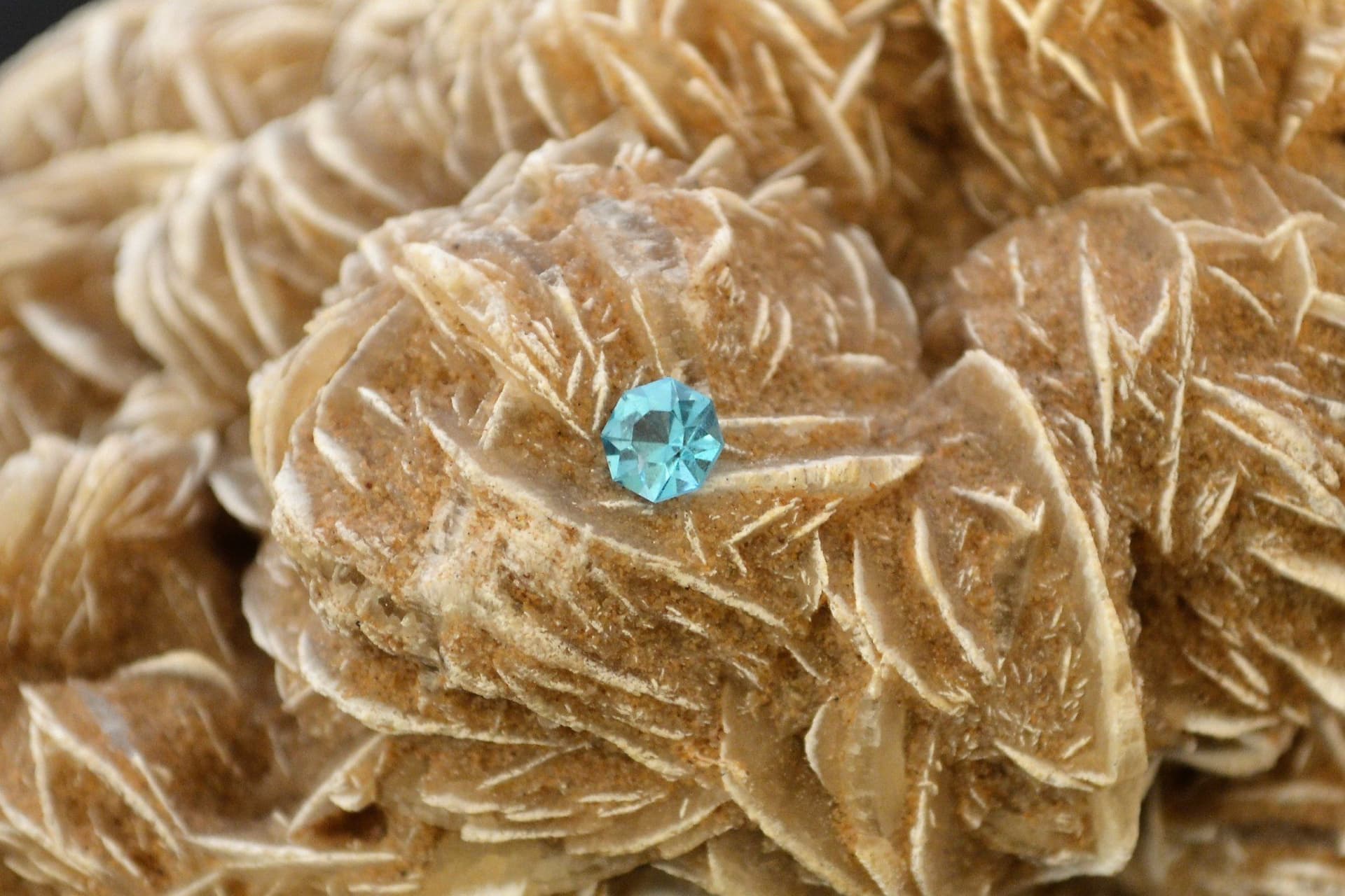 Kelly Lane's vivid blue faceted apatite resting on a mineral formation